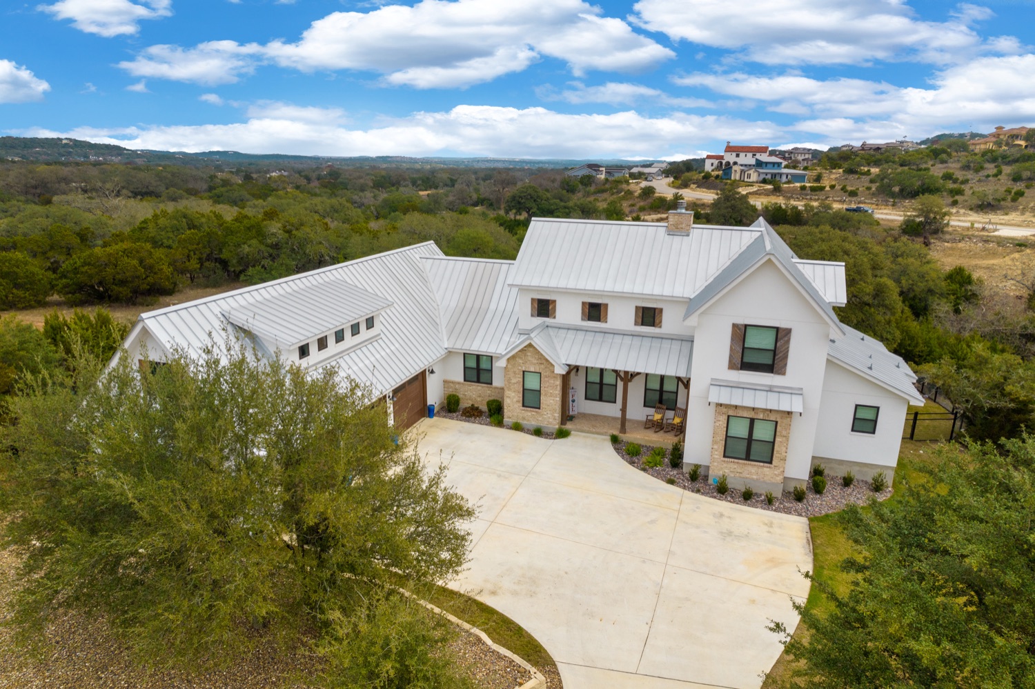 Aerial view of a modern farmhouse-style property and its grounds